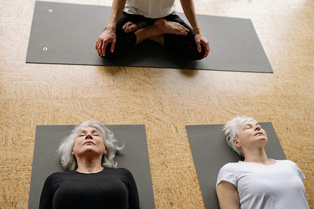 Two senior women practicing yoga in a studio setting for relaxation and well-being.